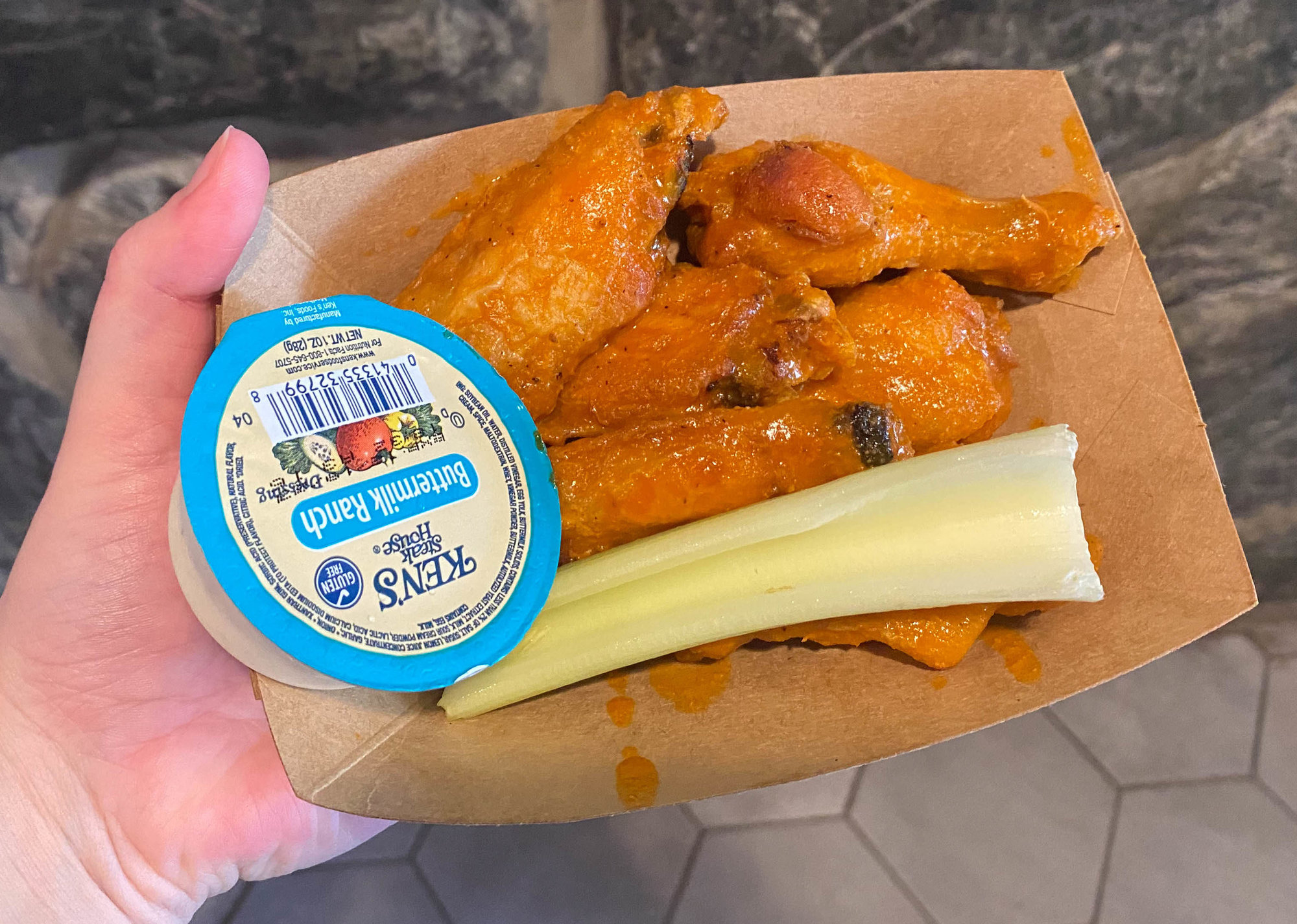 buffalo wings with celery and a blue cheese dip in a brown container